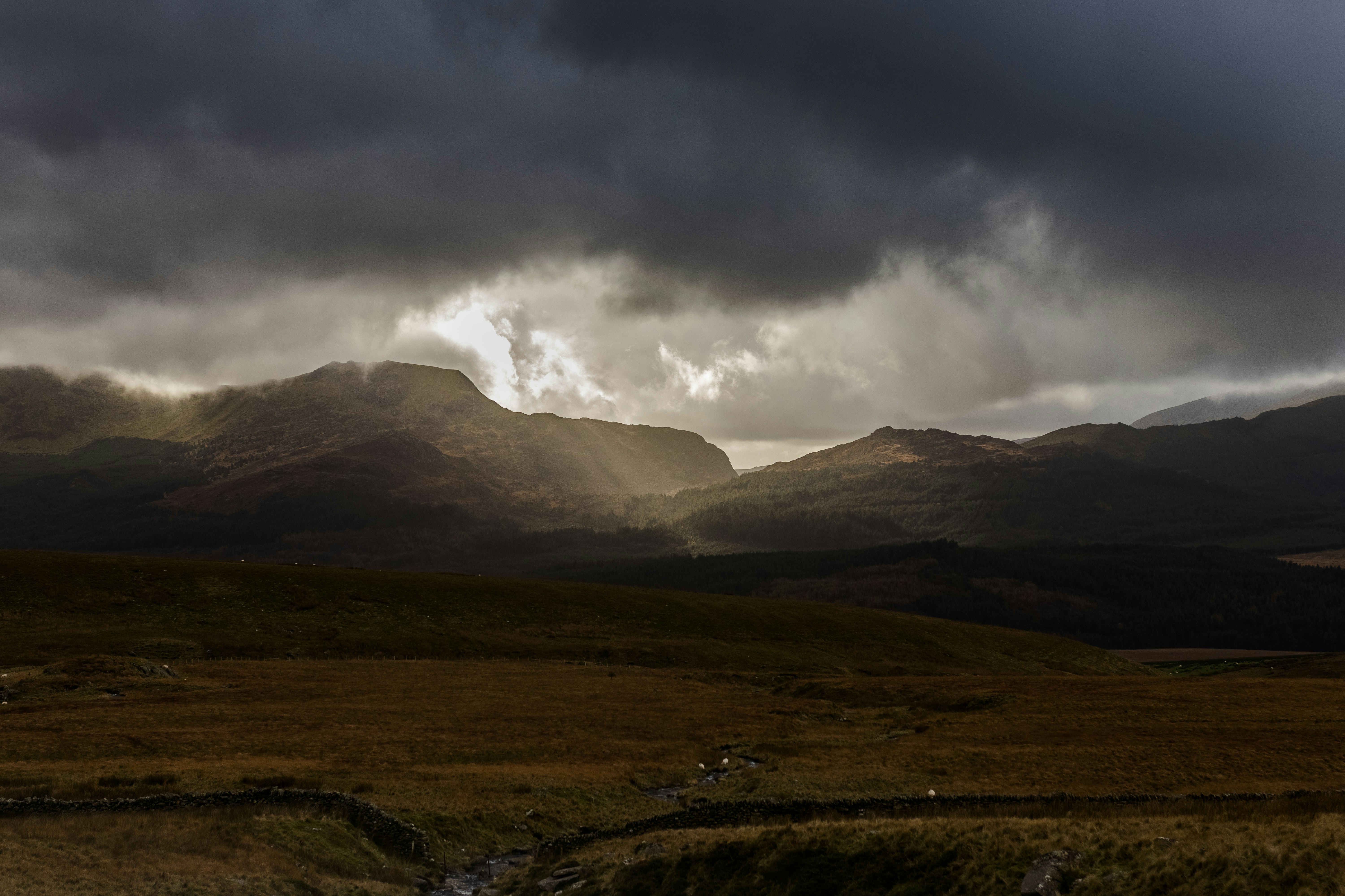 landscape photography of brown field near mountains with sun rays